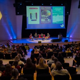 Foto van sprekers en bezoekers tijdens een talkshow in de Willem Burger Zaal in de Doelen in Rotterdam tijdens de Dag van van het Literatuuronderwijs 2022 op 22 november 2022.